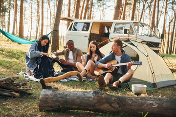 Camp and car. Group of young people is traveling together in the forest at daytime