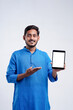 © PRASANNAPIX - Young indian man showing tablet over white background.