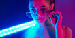 © standret - Holds neon lighting stick. Fashionable young woman standing in the studio