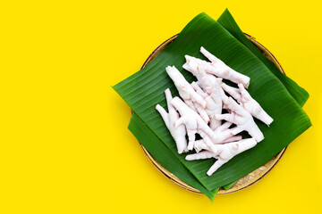 Wall Mural - Raw chicken feet in bamboo basket on yellow background.