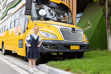 Back to school. Little girl from elementary school outdoor near yellow bus. Kid going learn new things 1th september