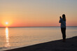 © Iuliia Pilipeichenko - Beautiful girl stands by the sea and looks at the dawn. Girl in travel. Amazing scenic outdoors view. Beautiful dawn on the seashore. Adventure lifestyle