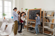 © Studio Romantic - Happy teacher and children playing games and having fun in class. Cheerful school students standing in front of classroom board and applauding classmate for good creative interesting presentation