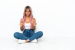 © luismolinero - Young mixed race woman with pink hair sitting on the floor isolated on white background celebrating a victory in winner position