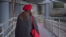 Back View Of Young Confident Elegant Woman Strolling In Urban City Looking Around. Stylish Caucasian Millennial In Spring Autumn Coat And Red Beret Walking In Slow Motion Outdoors