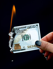 One hundred dollars are burning with fire in hand on a black