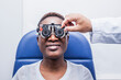 © ADDICTIVE STOCK - Black woman in optometry cabinet