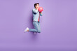 Full size profile side photo of young guy blow air balloon decoration prepare jump isolated over purple color background