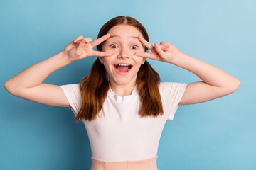 Poster - Photo of funny carefree person fingers show v-sign near eyes open mouth isolated on blue color background