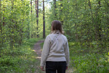 Fototapeta Las - a woman walks along a path in the forest