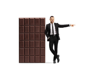 Sticker - Full length portrait of a businessman leaning on a big chocolate bar