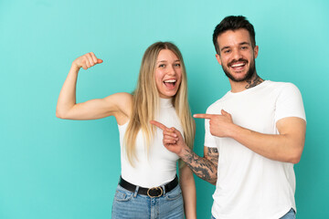 Young couple over isolated blue background making strong gesture