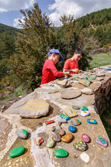 children friends play at decorating stones in a natural environment, painted stones in the foreground