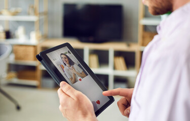 Young guy who wants to find love online looking at digital tablet display, liking profile pics and sending compliments to beautiful women on modern dating website or mobile app. Close up, closeup shot