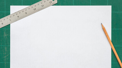Wall Mural - top view of blank paper page a4 on old green cutting mat with stainless steel ruler, pencil, copy sp