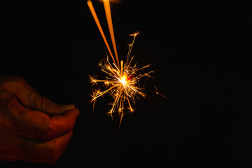 Wall Mural - people handle fireworks playing fun enjoy at night closeup fire sparkle.