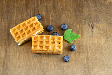 Wall Mural - Soft Belgian waffles with blueberries on the background of a brown wooden table with a natural pattern, a copy of the space. Rustic style