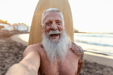 Happy Senior Surfer Taking Selfie While Having Fun Surfing At Sunset Time - Elderly Health People Lifestyle And Extreme Sport Concept