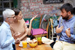 A young man arguing with his girlfriend and her Grandma while sitting in a bar. Leisure, bar, outdoor, friendship