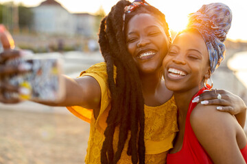 Happy girlfriends taking a selfie together outdoors
