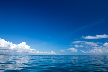 Wall Mural - clouds on blue sky over calm sea with sunlight reflection
