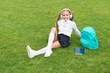 School holidays. Happy kid in school uniform sit on green grass. Have great summer