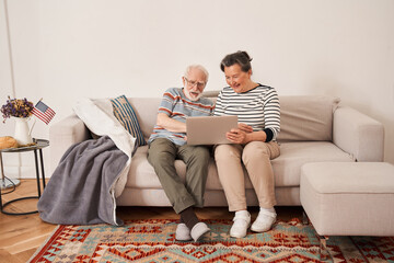 Wall Mural - Senior couple emotionally talking with relatives while sitting with laptop