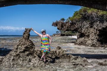 woman in a blue hat posing against the backdrop of corals and islands during low tide of the sea