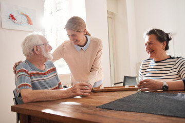 Wall Mural - Senior man looking at the nurse embracing him while sitting