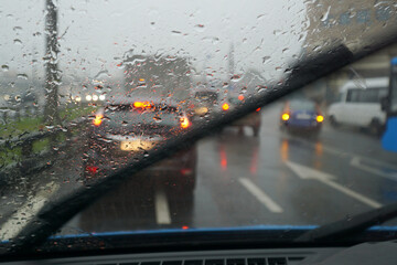  The view from the cab of the car on the road on a rainy day, when the windshield washers wipe the drops of water from the glass.