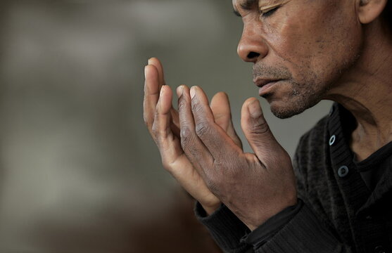 man praying to god with hands together Caribbean man with people praying stock photo