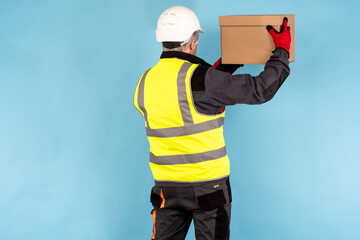 Poster - Box is in hands of a worker. Concept - he is an employee of order fulfillment center. Man working in a fulfillment warehouse. Standing man in a yellow vest. His back is turned to camera.
