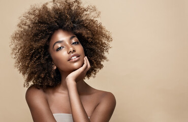 beauty portrait of african american woman with clean healthy skin on beige background. smiling dream