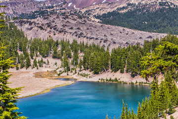 Wall Mural - clear blue alpine lake surrounded by fir trees and a large lava flow.