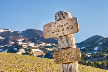Wall Mural - wooden signpost guides hikers along a trail to a distant volcanic mountain summit peak.
