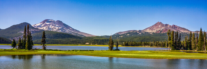 Wall Mural - panoramic view of mountain lake surrounded by fir trees and volcanic mountain peaks.