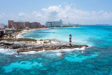 Aerial view of Punta Cancun Lighthouse. The Lighthouse adorned with white and red stripes and located in a rocky area.