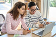 © insta_photos - Gen z latin girl and Asian guy classmates talking on class work looking at laptop computer. Diverse college students discussing online project in classroom. Collaborate international team concept.