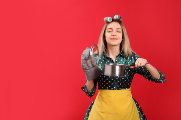 Wall Mural - Young housewife with saucepan on red background. Space for text