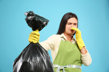 Sticker - Woman holding full garbage bag against light blue background, focus on hand