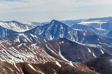 Sharp mountain peaks. Northern landscape. Mountains are covered with glaciers. View from helicopter flight altitude