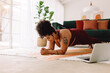 © (JLco) Julia Amaral - Healthy woman doing plank workout using laptop at home