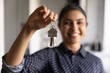 Happy Indian woman ready to move into new home. Real estate agent offering rent or buying house, flat, apartment, help with loan and mortgage. Hand of buyer or home owner holding key. Closeup