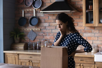 Disappointed customer getting and opening box from internet store, looking at damaged goods. Dissatisfied shopper woman receiving wrong parcel. Delivery service error, courier service mistake concept