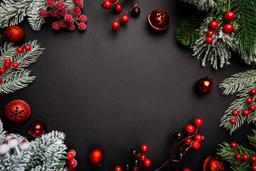 Wall Mural - christmas holidays composition with red berries and fir tree branches on black background with copy 
