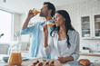 © gstockstudio - Young couple drinking orange juice while spending time in the domestic kitchen
