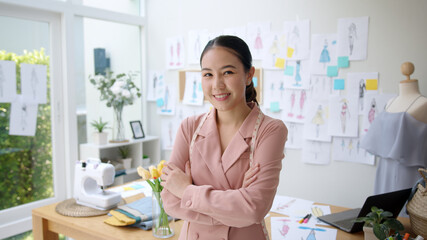 Wall Mural - Young asia people female arm cross relax smile happy look camera work on desk at textile home office modern studio in finance loan fund for sme job digital social e-commerce sell dress online store.