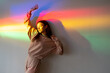 © golubovy - Rainbow light female. Peace energy. Carefree youth. Find enjoyment. Relaxed satisfied stretching young girl on smooth fantasy rainbow color neon light wall.