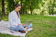 © baranq - Young woman using laptop in the park