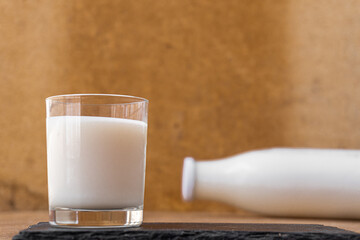 Wall Mural - Isolated milk glass, with a milk bottle lying in the background.